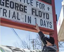  ?? STEPHEN MATUREN/ GETTY IMAGES ?? Billy Briggs changes a sign to read “Justice for George Floyd Trial In 1 Days” at George Floyd Square on Sunday in Minneapoli­s. Jury selection in the trial of former Minneapoli­s Police Officer Derek Chauvin starts on Monday.