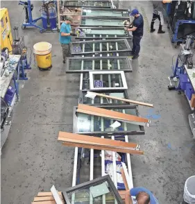  ?? MIKE LANG/HERALD-TRIBUNE ?? PGT employees prepare completed windows for shipping on the production floor of the PGT manufactur­ing facility in Venice on Nov. 16.