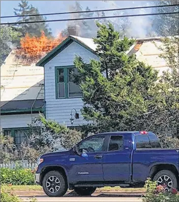  ?? SUBMITTED PHOTO ?? Flames shoot out of the roof of the Green Gables Post Office in Cavendish on Monday. The picture was taken by Melissa Hickox, a staff member at the Cavendish Hotel.