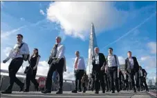  ?? Justin Tallis AFP/Getty Images ?? COMMUTERS stroll across London Bridge while behind them, London’s the Shard, just added to London Pass attraction­s, looms.
