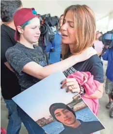  ?? WILFREDO LEE/AP ?? Patricia Oliver holds a picture of her son, Joaquin Oliver, one of 17 people killed earlier this year at Marjory Stoneman Douglas High School, as she hugs Caspen Becher outside a Publix Supermarke­t in Coral Springs, Fla., on Friday. Students from the...