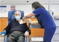  ??  ?? Michalis Giovanidis, a care home resident, receives a dose of the Covid-19 vaccine in Athens yesterday