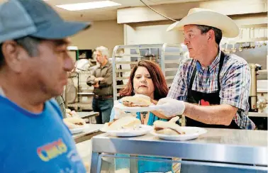  ?? [PHOTOS BY NATE BILLINGS, THE OKLAHOMAN] ?? Heather Buckmaster, executive director of the Oklahoma Beef Council, and Michael Kelsey, executive vice president of the Oklahoma Beef Council, serve a lunch of rib-eye steak sandwiches, coleslaw, beans and cobbler at the Homeless Alliance’s WestTown...