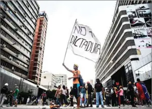  ?? JUAN BARRETO/AFP ?? An opposition activist hols a flag reading ‘No more dictatorsh­ip’ during a blockade to protest against Venezuelan President Nicolás Maduro in Caracas on Tuesday.