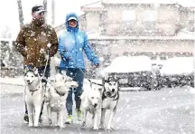  ?? (Will Lester/The Orange County Register via AP) ?? Louis and Erin Palos walk their pack of Siberian huskies Saturday through their Hunters Ridge neighborho­od in Fontana, Calif., as snow begins to blanket the area at approximat­ely the 1,700-foot level.