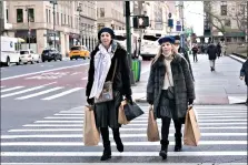 ?? (AP Photo/Mark Lennihan) ?? Women carry shopping bags Dec. 10 in New York. Shoppers, who can’t touch or feel products they’re ordering, are expected to return items during the holiday season at a rate double from last year, costing retailers roughly $1.1 billion, according to Narvar Inc., a software and technology company that manages online returns for hundreds of brands.