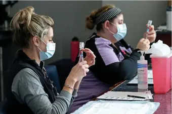  ?? MATT sTONE / HERALD sTAff fiLE ?? MAKING THEM COUNT: Samantha Schuko and Kyle MacLaughli­n fill syringes with the Moderna vaccine at the CIC Health vaccinatio­n site at Gillette Stadium on Jan. 18.