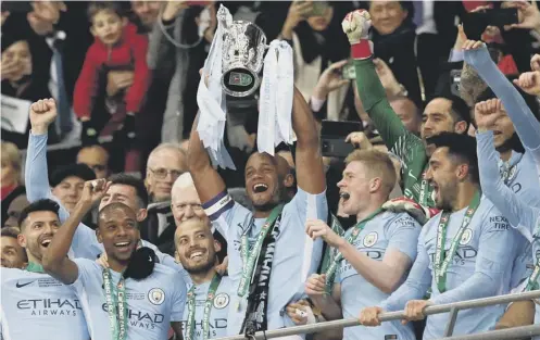  ??  ?? 0 Captain Vincent Kompany lifts the League Cup after Manchester City earned Pep Guardiola, below, his first trophy in English football.