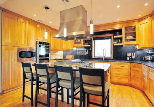  ?? PHOTOS: Larry Wong/ Edmonto n Journal ?? The new home is built in a modernized arts and crafts style. The north-facing open kitchen is well lit, with sparkly pendant lamps over the island as well as natural light that floods the room from a second-floor skylight.