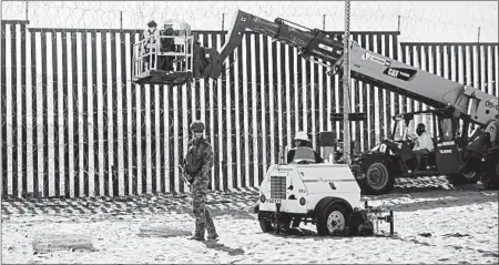  ?? ARIANA DREHSLER/GETTY-AFP ?? A Border Patrol officer stands guard Friday as work crews reinforce the border fence in San Diego. U.S. military troops are barred from conducting law enforcemen­t duties.