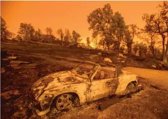  ?? NOAH BERGER/AP ?? Wildfires cast an orange glow on a scorched car Friday at a residence in Redding, Calif.