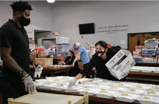  ??  ?? Marsh McKnight and Thalia Salinas, both with Spice of Life catering, prepare dinner plates for clients at Church Under the Bridge.