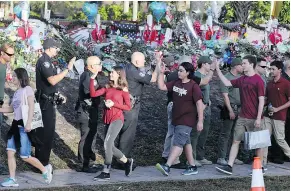  ?? — THE ASSOCIATED PRESS ?? Police greet students returning to Marjory Stoneman Douglas High School on Wednesday in Parkland, Fla.