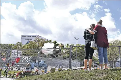  ?? MATT MCCLAIN/WASHINGTON POST ?? Hadley Sorensen, 16, is embraced by her mother, Stacy Sorensen, as people gather outside Marjory Stoneman Douglas High School in Parkland, Fla., after a shooting there Feb. 14.