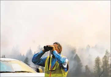  ??  ?? PG& E EMPLOYEE Frank Hock surveys a utility transmissi­on line as crews work to contain the Glass f ire in Napa County in St. Helena. With no containmen­t in sight Sunday night, PG& E cut power to 65,000 customers.