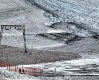  ?? FOTO: KARL-JOSEF HILDENBRAN­D/DPA ?? Grau statt weiß: Ausflügler gehen auf Schneerest­en des Schneefern­er-Gletscher auf dem Zugspitzpl­att einen Hang hinauf.