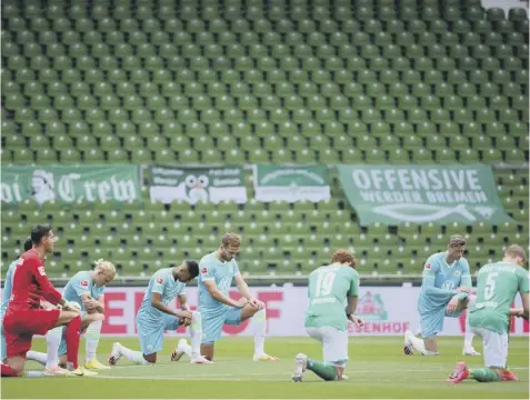  ??  ?? 0 Players from Werder Bremen and Wolfsburg kneel together at the centre circle prior to yesterday’s Bundesliga match.
