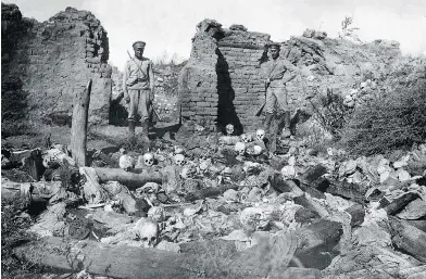  ?? ARMENIAN GENOCIDE MUSEUM-INSTITUTE / AFP / GETTY IMAGES ?? A picture released by the Armenian Genocide Museum-Institute dated 1915 purportedl­y shows soldiers standing over skulls of victims from the Armenian village of Sheyxalan during the First World War.