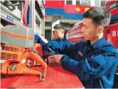  ??  ?? Zhang (right) and his colleagues clean a fire engine.