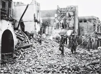  ?? Picture: AFP ?? Indian soldiers walking through the debris of a building in the Chow Bijli Wala area of Amristar during unrest following the Partition of India and Pakistan in August 1947.
