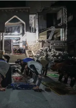  ?? ?? Palestinia­n citizens perform Tarawih prayers on the first day of Ramadan amid the rubble of the Al-Huda Mosque in Rafah, which was partially destroyed by Israeli air strikes