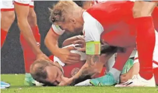  ?? // AFP ?? Los jugadores de la selección danesa auxilian con rapidez a Eriksen y tratan de que su compañero no se trague la lengua