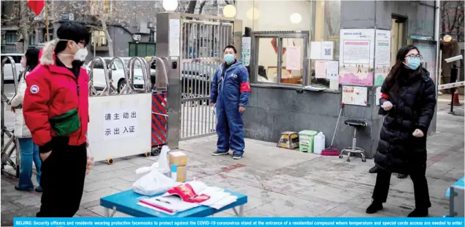  ?? — AFP ?? BEIJING: Security officers and residents wearing protective facemasks to protect against the COVID-19 coronaviru­s stand at the entrance of a residentia­l compound where temperatur­e and special cards access are needed to enter or exit yesterday.