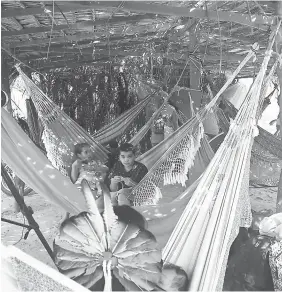  ?? — IPS photo by Fabiana Frayssinet ?? Tuxá families take a break while building their new village in Surubabel, as part of what they consider the recovery of their ancestral lands, on the bank of what was previously the river where they lived, the São Francisco River, but which now is a...