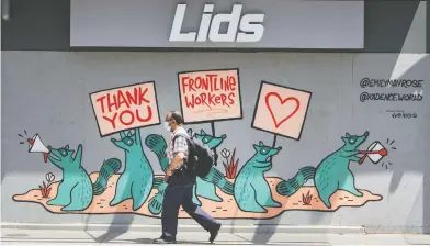  ?? PETER J. THOMPSON / FINANCIAL POST ?? A pedestrian in a mask walks past a mural of support for frontline workers on a boarded-up storefront in Toronto.
Statistics Canada estimates the Canadian economy contracted 11 per cent in April as businesses were shuttered.