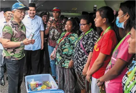  ?? ?? Sultan abdullah speaking with flood victims while distributi­ng aid at a shelter in Rompin. — Bernama