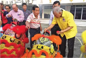  ??  ?? Ting (right) performs the eye dotting on one of the school’s ‘lions’ while others look on.