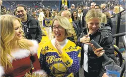  ??  ?? Robin Schreiber, center, mingles with fans and a member of the Warriors Dance Team, left, at a Golden StateWarri­ors game in December.