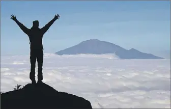  ?? Photograph­s by Jack Dolan Los Angeles Times ?? GUIDE ANDREW MAFIE offers a prayer of gratitude on the 19,341-foot summit of Mt. Kilimanjar­o.