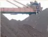  ?? — Reuters ?? Workers are seen on the top of an iron ore pile as a machine works on blending the iron ore, at Dalian Port, China.