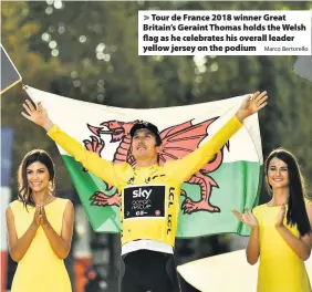  ?? Marco Bertorello ?? &gt; Tour de France 2018 winner Great Britain’s Geraint Thomas holds the Welsh flag as he celebrates his overall leader yellow jersey on the podium