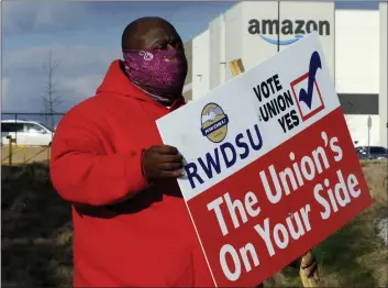  ?? JAY REEVES — AP PHOTO ?? Michael Foster of the Retail, Wholesale and Department Store Union holds a sign outside an Amazon facility in February where labor is trying to organize workers.