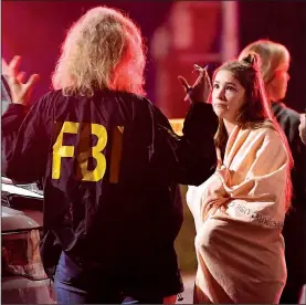  ?? AP/MARK J. TERRILL ?? An FBI agent talks to a woman early Thursday near the country-music bar in Thousand Oaks, Calif., where a gunman opened fire as people line-danced on “College Country Night.”