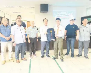  ?? ?? SUMBANGAN: Lidam (tengah) menyampaik­an beg sekolah dan alat tulis sumbangan Yayasan PEKEMA Sarawak kepada salah seorang penerima.