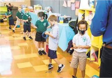  ?? EDUARDO CONTRERAS U-T ?? Los estudiante­s de kínder hacen fila para el laboratori­o de computació­n en la escuela católica St. Columba.