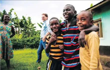  ?? KEVIN BROWN/MIGHTY ALLY ?? Two clients of Kyaninga Child Developmen­t Centre pose with their friend outside their home, as mom Kemisiga Rose and Steve Williams of KCDC look on.