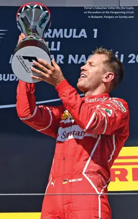  ?? (AFP) ?? Ferrari's Sebastian Vettel lifts the trophy on the podium at the Hungarorin­g circuit in Budapest, Hungary on Sunday