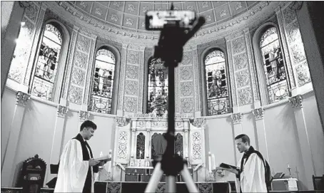  ?? EMILY LESHNER/AP ?? The Rev. Steven Paulikas, right, and curate Spencer Cantrell deliver an Evening Prayer service over Facebook Live in March in New York City.