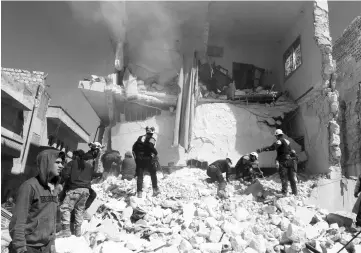  ??  ?? People and civil defence personnel remove rubble as they look for survivors at a damaged site after an air strike on rebel-held Idlib city, Syria. — Reuters photo