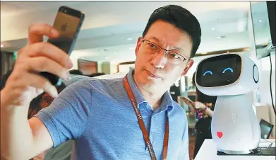  ?? KIM KYUNG-HOON / REUTERS ?? A visitor takes a selfie with Baidu’s robot Xiaodu at the 2015 Baidu World Conference in Beijing.