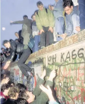  ??  ?? WALL OVER Protesters join forces to tear down Berlin landmark. Picture: AFP/Getty Images