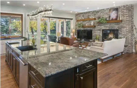  ??  ?? A folding Tesoro patio door allows for a seamless flow of traffic between the great room and outdoors, making it an integrated extension of the home. Cherry wood shelves are anchored to the Chicago brick wall above a Cambria Black quartz hearth.