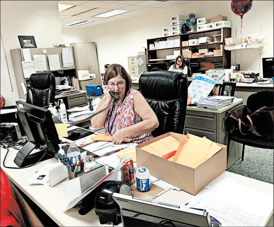  ?? AMY LAVALLEY/POST-TRIBUNE ?? Barbara Gamble, of Portage, a part-time employee in Porter County Elections and Voter Registrati­on, stuffs envelopes with flyers in preparatio­n for absentee ballots while taking a phone call Tuesday in the department’s office in the administra­tion building in downtown Valparaiso.