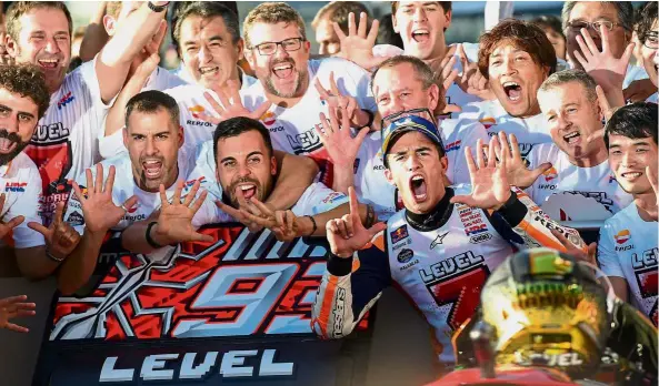  ??  ?? Sheer joy: Marc Marquez celebrates in the pits with his crew after winning his fifth world MotoGP title at the Twin Ring Motegi Circuit yesterday. Marquez indicates with his fingers his seven world titles, with the other two coming from the 125cc and Moto2 categories. — AFP