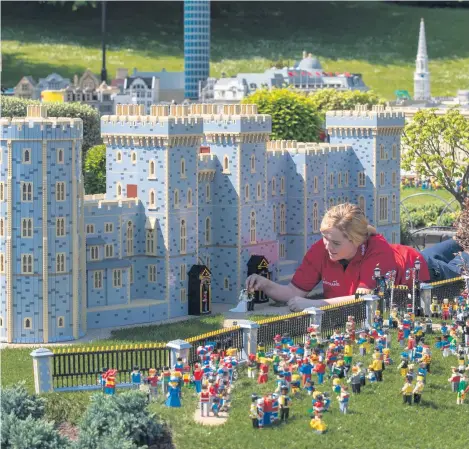 ??  ?? Model-maker Lucy Gullon puts the finishing touches to a scene created at Legoland’s Windsor resort depicting the forthcomin­g wedding of Prince Harry and Meghan Markle. It comes complete with a 39,960 brick version of Windsor Castle which took a team of...