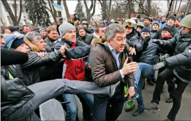  ?? REUTERS ?? Anti-government protesters attack a deputy of the Party of Regions Vitaly Grushevsky outside the Ukrainian Parliament building in Kiev on Saturday. Protesters seized the Kiev office of President Viktor Yanukovich on Saturday and the opposition demanded...